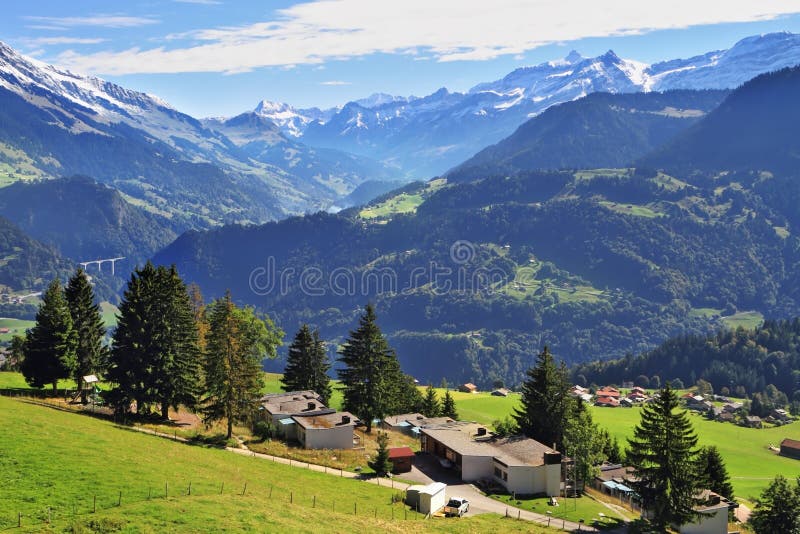 Picturesque gentle alpine meadows and rural houses chalets with red roofs. Gorgeous weather in the resort town of Leysin in the Swiss Alps. Picturesque gentle alpine meadows and rural houses chalets with red roofs. Gorgeous weather in the resort town of Leysin in the Swiss Alps