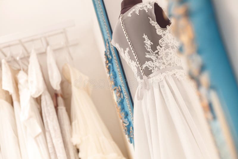 Beautiful wedding dress on mannequin in atelier. Various bridal clothing in hanging on background. Beautiful wedding dress on mannequin in atelier. Various bridal clothing in hanging on background