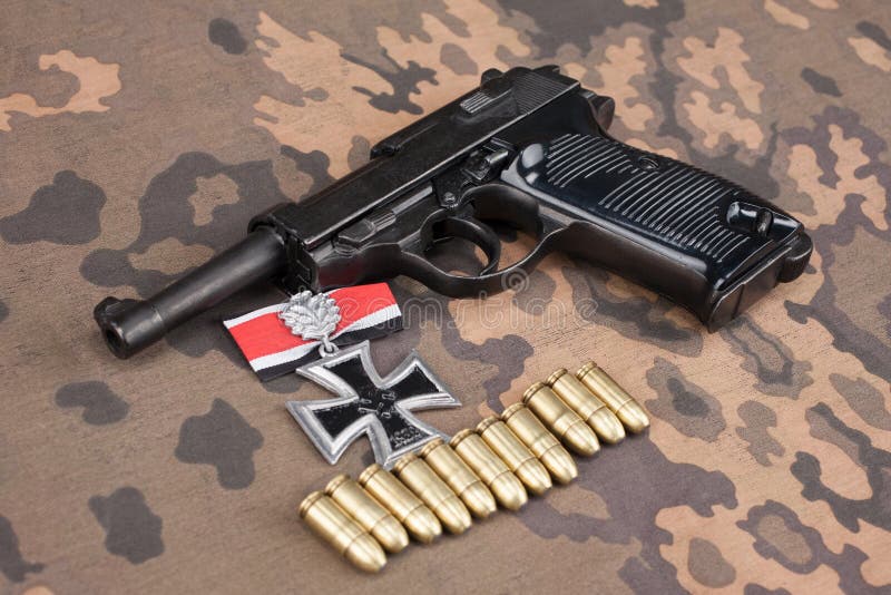 WWII era nazi german army 9 mm semi-automatic pistol with Iron Cross award. On camouflaged uniform background