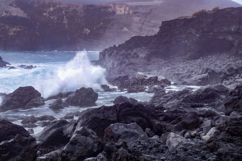 Waves crash against the rocky shoreline of Capelinhos in the Azores Islands as a thunderstorm subsides, with an oil painting effect. Waves crash against the rocky shoreline of Capelinhos in the Azores Islands as a thunderstorm subsides, with an oil painting effect