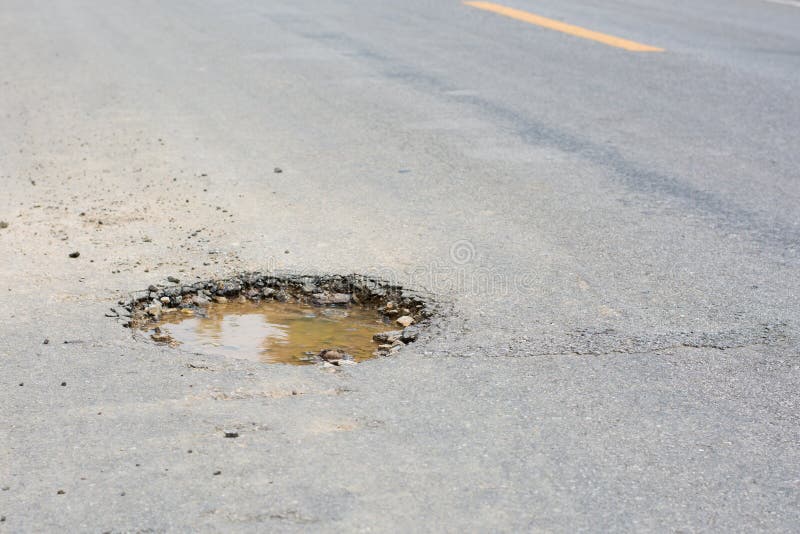 Water in the dangerous pothole on the road. Water in the dangerous pothole on the road