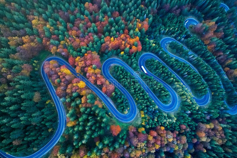 Curved road trough the colorful autumn forest; pass in Transylvania Romania, aerial view from drone. Curved road trough the colorful autumn forest; pass in Transylvania Romania, aerial view from drone