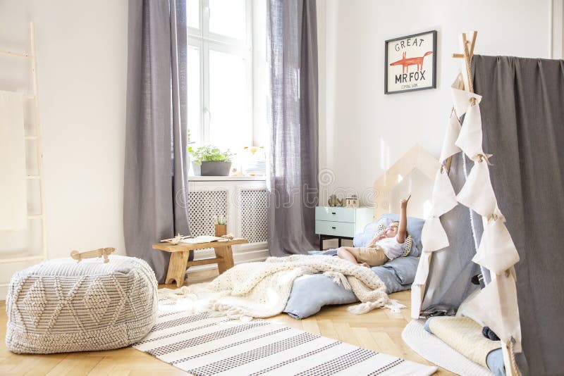 Comfortable bed in scandinavian kid`s bedroom with grey tent and big pouf, real photo with mockup on the wall. Comfortable bed in scandinavian kid`s bedroom with grey tent and big pouf, real photo with mockup on the wall