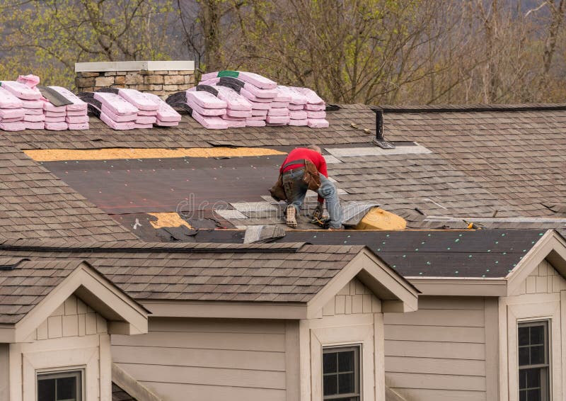 Roofing contractor removing the old tiles before replacing with new shingles on a townhouse roof. Roofing contractor removing the old tiles before replacing with new shingles on a townhouse roof