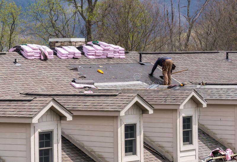 Roofing contractor removing the old tiles before replacing with new shingles on a townhouse roof. Roofing contractor removing the old tiles before replacing with new shingles on a townhouse roof