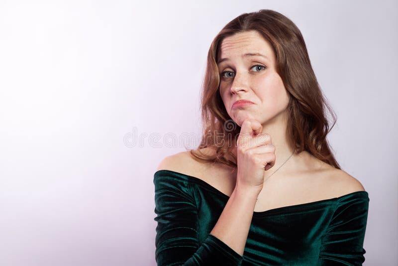 I don`t know. Portrait of unhappy thoughtful woman with freckles and classic green dress. studio shot on silver gray background. I don`t know. Portrait of unhappy thoughtful woman with freckles and classic green dress. studio shot on silver gray background.