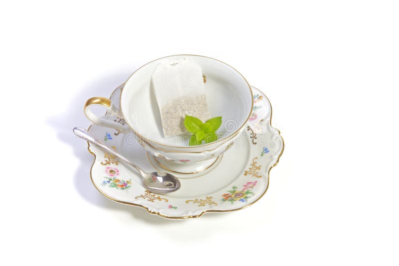 Delicate porcelian cup of tea with a teabag and mint. Delicate porcelian cup of tea with a teabag and mint