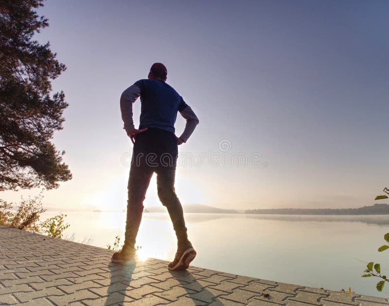 Wysoki szczupły mężczyzna biega wzdłuż jeziora w parku w pogodnym brzasku fotografia royalty free Wysoki szczupły mężczyzna biega wzdłuż jeziora w parku w pogodnym brzasku fotografia royalty free