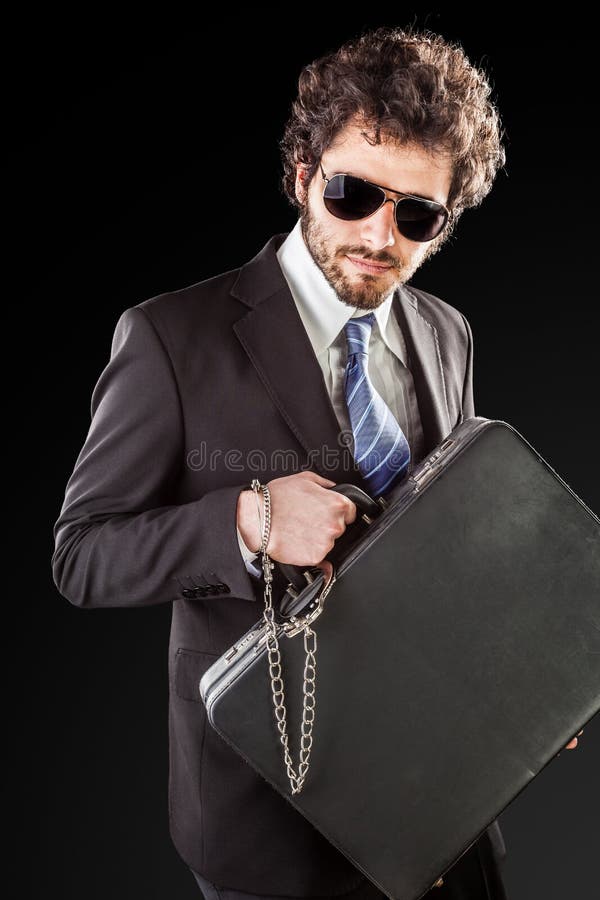 Businessman wearing a suit with a secure suitcase attached with handcuffs. Businessman wearing a suit with a secure suitcase attached with handcuffs