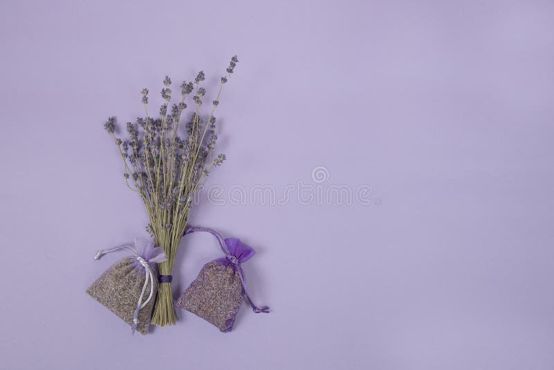 Wysuszeni lavander kwiaty i lawendowe saszetki na lawendowym barwionym tle obrazy stock Wysuszeni lavander kwiaty i lawendowe saszetki na lawendowym barwionym tle obrazy stock