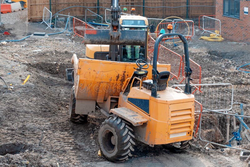 Excavator loading dumper during groundworks on a new residential housing construction site. Excavator loading dumper during groundworks on a new residential housing construction site