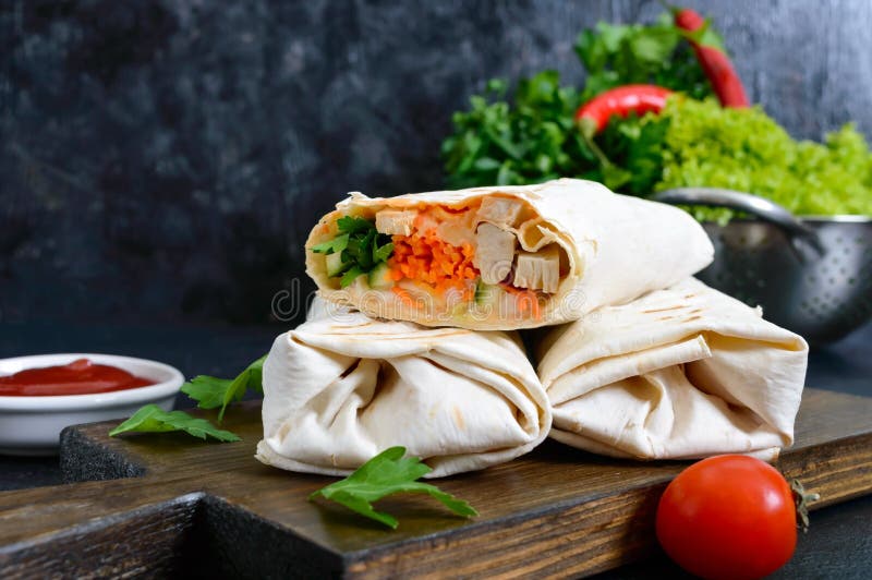 Wyśmienicie shawarma kanapka na czarnym tle Burritos opakunki z piec na grillu kurczakiem warzywami i, zielenie fotografia stock Wyśmienicie shawarma kanapka na czarnym tle Burritos opakunki z piec na grillu kurczakiem warzywami i, zielenie fotografia stock