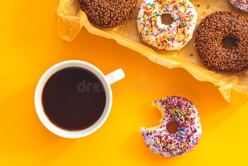 Wyśmienicie oszkleni donuts w pudełku i filiżance kawy na kolorze żółtym ukazują się zdjęcie royalty free Wyśmienicie oszkleni donuts w pudełku i filiżance kawy na kolorze żółtym ukazują się zdjęcie royalty free