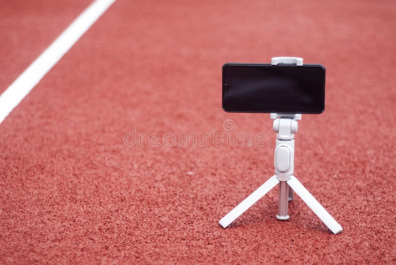 Wyśmiewa w górę czarnego smartphone z tripod Bielu ekran dla projekta szablonu na tle czerwony ślad dla fotografia stock Wyśmiewa w górę czarnego smartphone z tripod Bielu ekran dla projekta szablonu na tle czerwony ślad dla fotografia stock