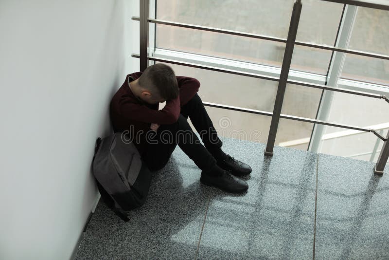 Wzburzona chłopiec siedzi blisko okno indoors z plecakiem