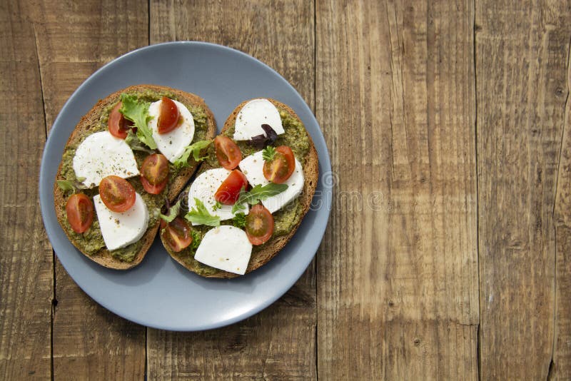 Wznosi toast kanapki mozzarelli ser, czereśniowych pomidory i pesto bruschetta, grzanka na drewnianym tle Zdrowy ?niadanie, przek obrazy stock Wznosi toast kanapki mozzarelli ser, czereśniowych pomidory i pesto bruschetta, grzanka na drewnianym tle Zdrowy ?niadanie, przek obrazy stock