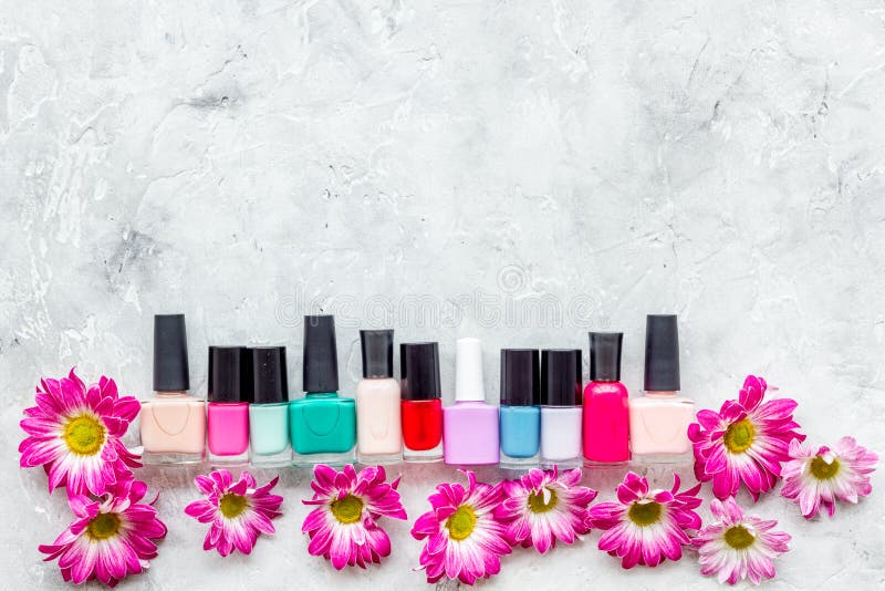 Choose nail polish for manicure. Bottles of colored polish on grey background top view. Choose nail polish for manicure. Bottles of colored polish on grey background top view.