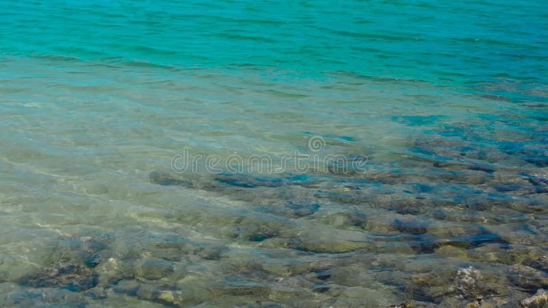 Wässern Sie Oberflächen- und Kräuselungswellen im ruhigen Meer mit Steinen auf sandiger Unterseite Blaues Wasser im ruhigen See u