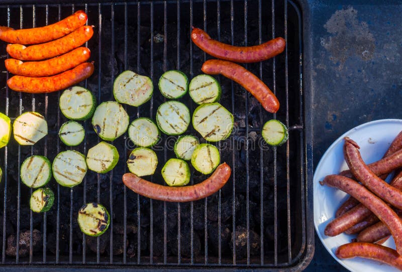 Würste und Frischgemüsezucchini, die draußen auf einem Grill grillt lizenzfreie stockfotos Würste und Frischgemüsezucchini, die draußen auf einem Grill grillt lizenzfreie stockfotos