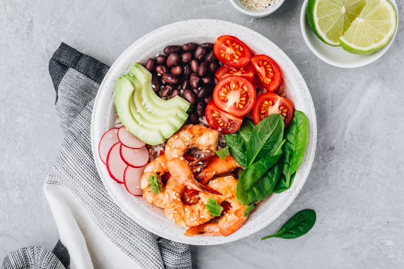 Würzige Garnele Burrito-Buddha-Schüssel mit Wildreisen, Spinat, Rettich, Tomaten, schwarzen Bohnen und Avocado lizenzfreies stockbild