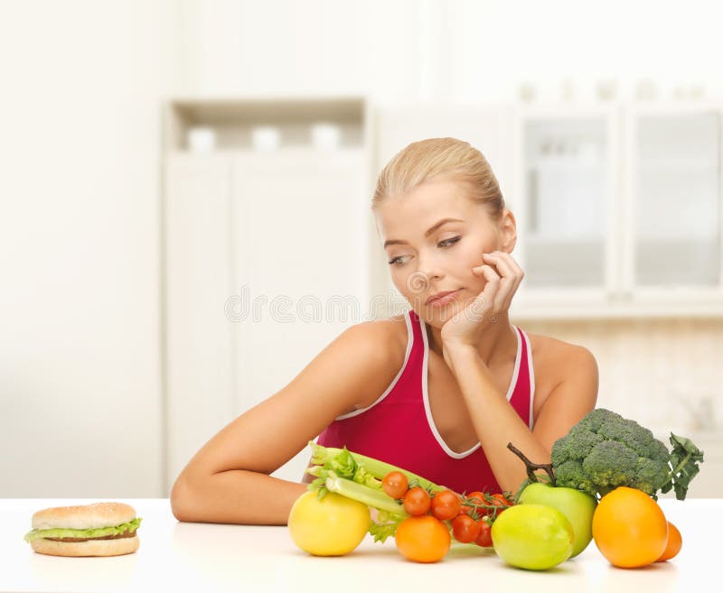 Fitness, diet and food concept - doubting woman with fruits and hamburger. Fitness, diet and food concept - doubting woman with fruits and hamburger