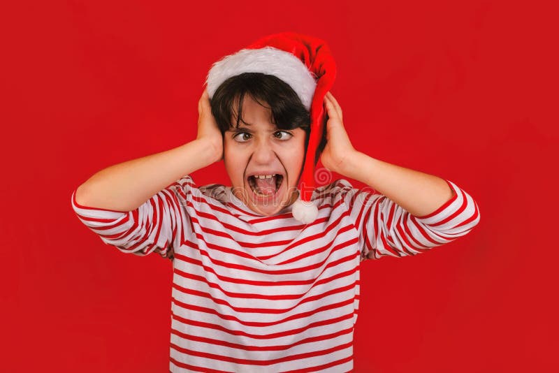 Wściekły dzieciak noszący kapelusz z santa claue z rękami na głowie zdjęcia stock