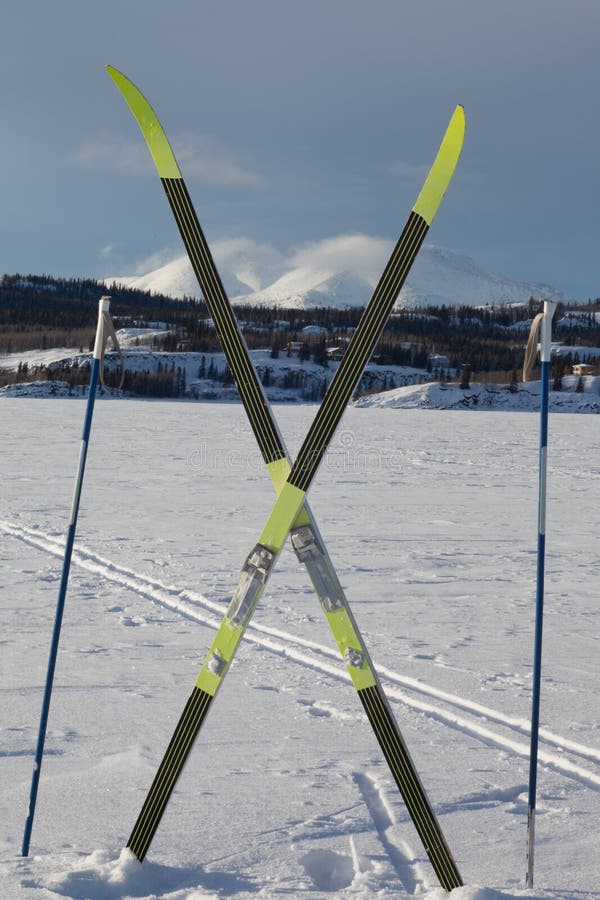 Cross country skiing. Skis and poles near ski track on frozen lake. Perfect winter snow conditions with blue sky. Cross country skiing. Skis and poles near ski track on frozen lake. Perfect winter snow conditions with blue sky.