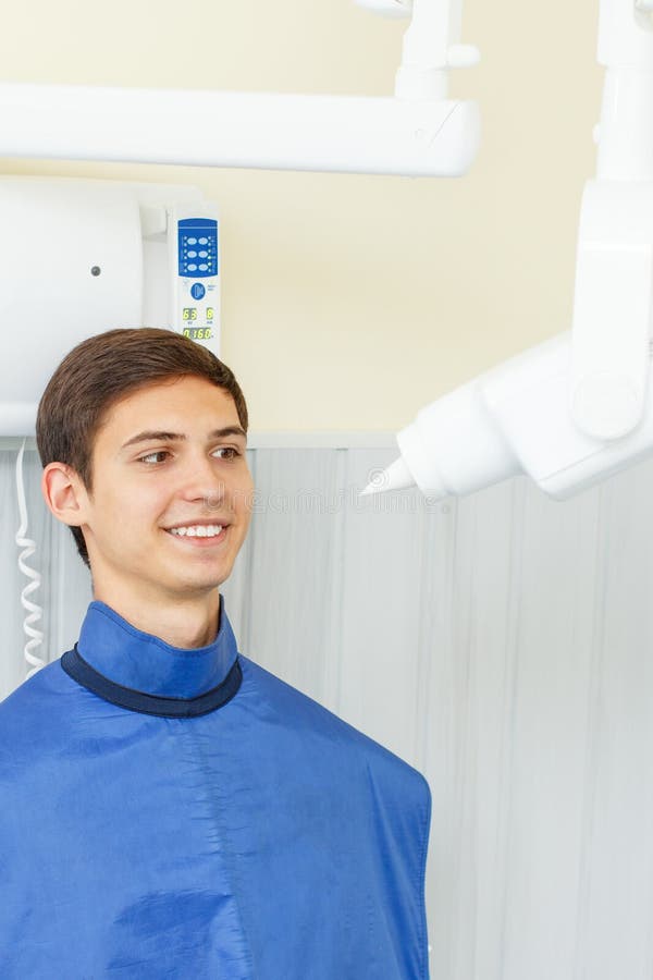 Xray Machine and Handsome Young Man in a Dental Office Stock Image