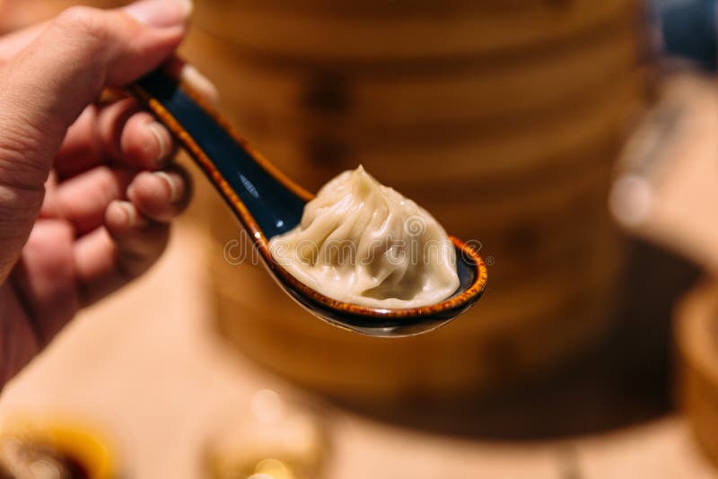 Xiao Long Bao Soup Dumpling in spoon with blur bamboo streamer basket in background