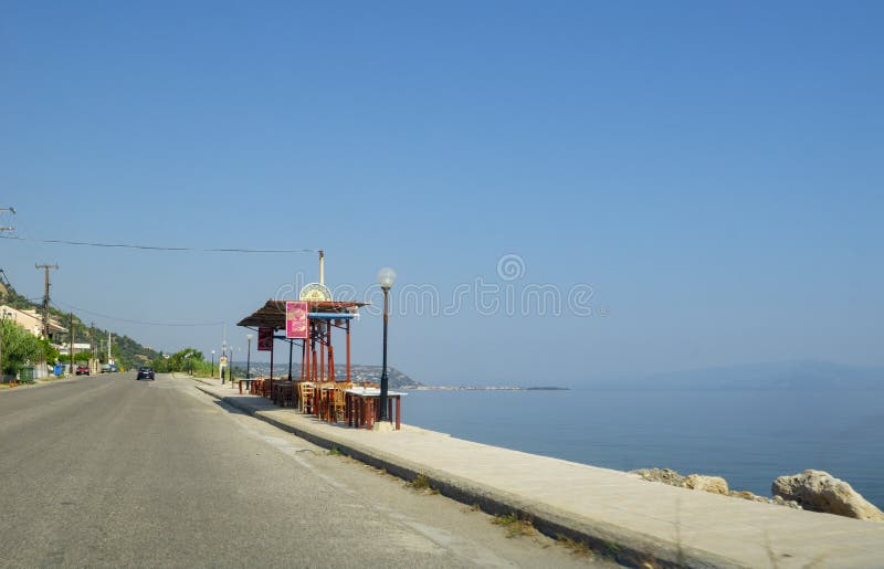 Restaurant tables and chairs set up on footpath along seaside and between sea and highway stock photography Restaurant tables and chairs set up on footpath along seaside and between sea and highway stock photography