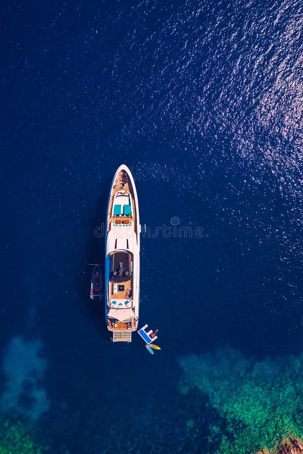 Yacht anchoring in crystal clear turquoise water in front of the tropical island, alternative lifestyle, living on a boat. Aerial