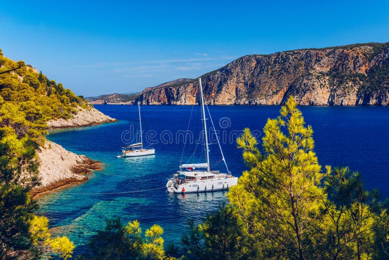 Yacht anchoring in crystal clear turquoise water in front of the tropical island, alternative lifestyle, living on a boat. Aerial