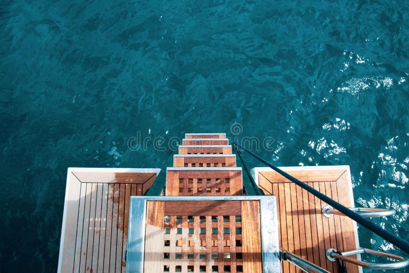 Yacht Life: the rear deck of a luxury yacht, view from above, on a turquoise, mediterranean sea. Private cruise