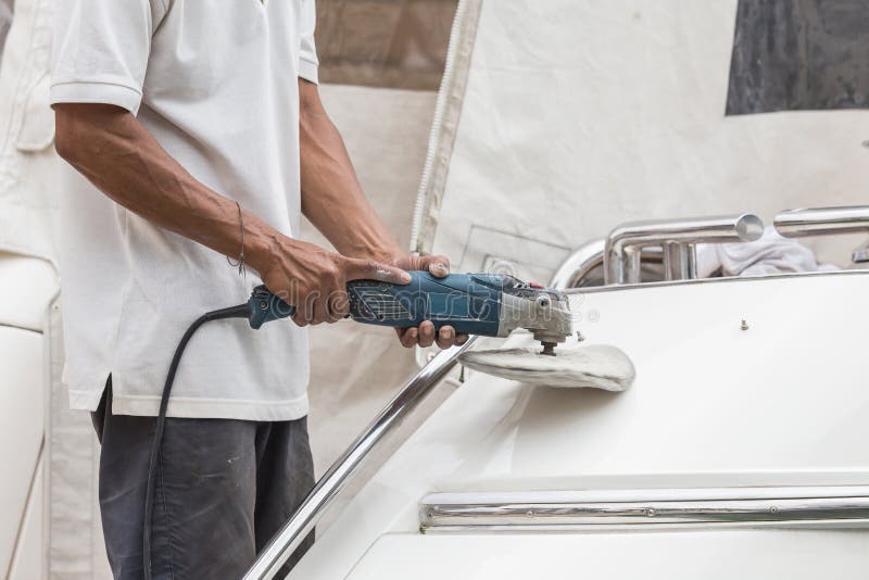 Yacht maintenance. A man polishing side of the white boat in the