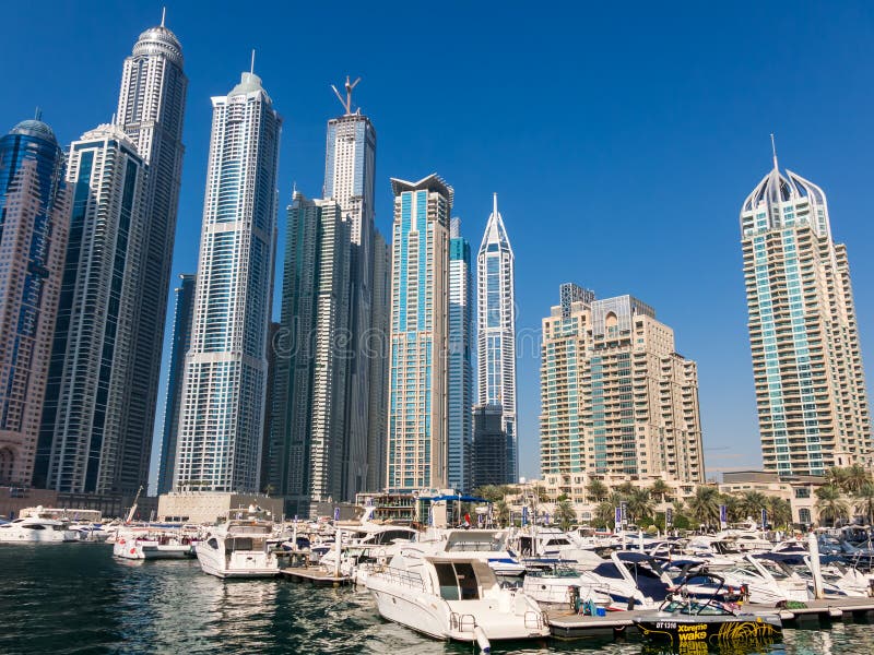 Yachts and speedboats in the marina with highrise buildings in the background of Marina district of Dubai, United Arab Emirates. Yachts and speedboats in the marina with highrise buildings in the background of Marina district of Dubai, United Arab Emirates