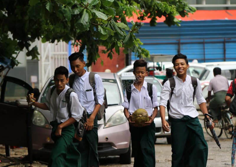 Four collegians in Myanmarese uniform of college white shirt and green Long Yi walking homing on the street after school program stock image Four collegians in Myanmarese uniform of college white shirt and green Long Yi walking homing on the street after school program stock image