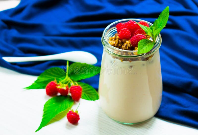 Yaourt Avec Des Baies De Framboise Et Muesli, Décoré Des Feuilles En Bon  état, Dans Un Petit Pot En Verre Sur Une Table Blanche a Photo stock -  Image du normal, croustillant