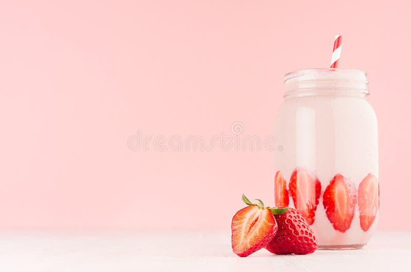 Yaourt doux de fraise en baie mûre coupée en tranches décorée par pot et paille rayée rouge sur le fond rose en pastel mou, l'esp photographie stock Yaourt doux de fraise en baie mûre coupée en tranches décorée par pot et paille rayée rouge sur le fond rose en pastel mou, l'esp photographie stock