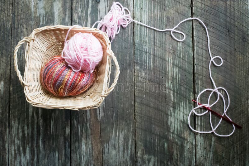 Pastel colored yarn in white basket and wooden crochet hooks of