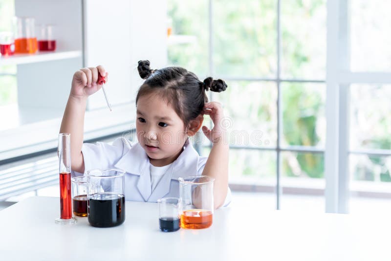 A 4 year old Asian girl wearing a white scientist uniform Learning And conducted a scientific