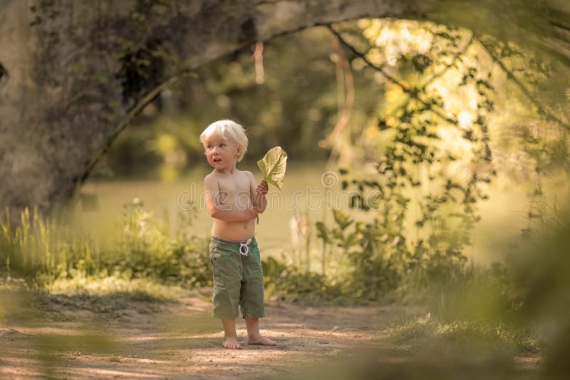 A 4-year-old Boy Barefoot in Shorts Runs Along a Forest Path Near the ...