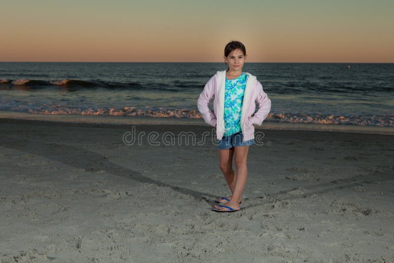 8 Year old girl sitting on beach at dusk Stock Photo