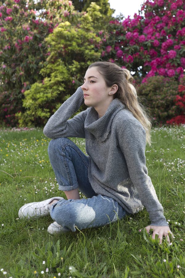 16 Year Old Teenager Sitting in a Park with Grass and Flowers. Stock ...