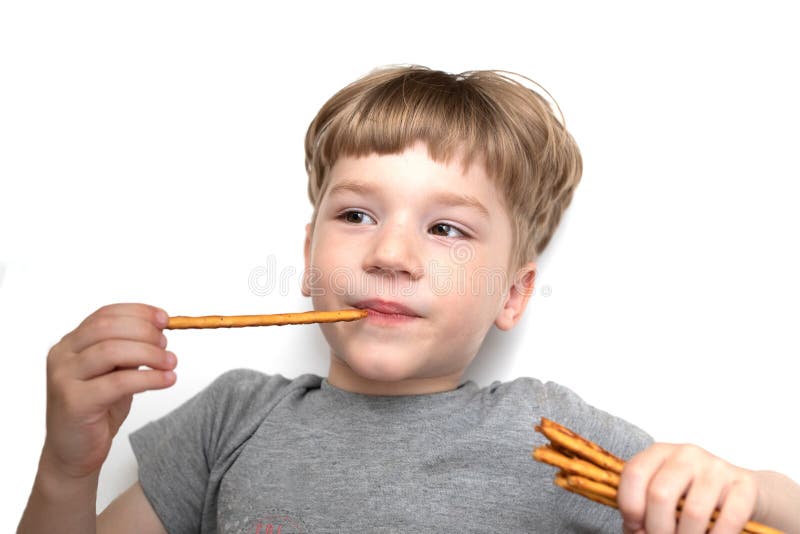 5 years old boy eats bread sticks on white background, crispy snack with poppy seeds royalty free stock photo