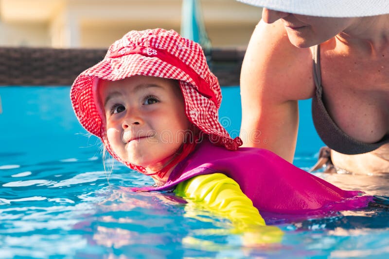 2-3 years old child with mother in swimming pool learn to swim. Summer at home concept