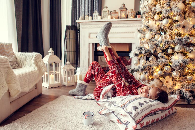 Child relaxing by Christmas tree at home