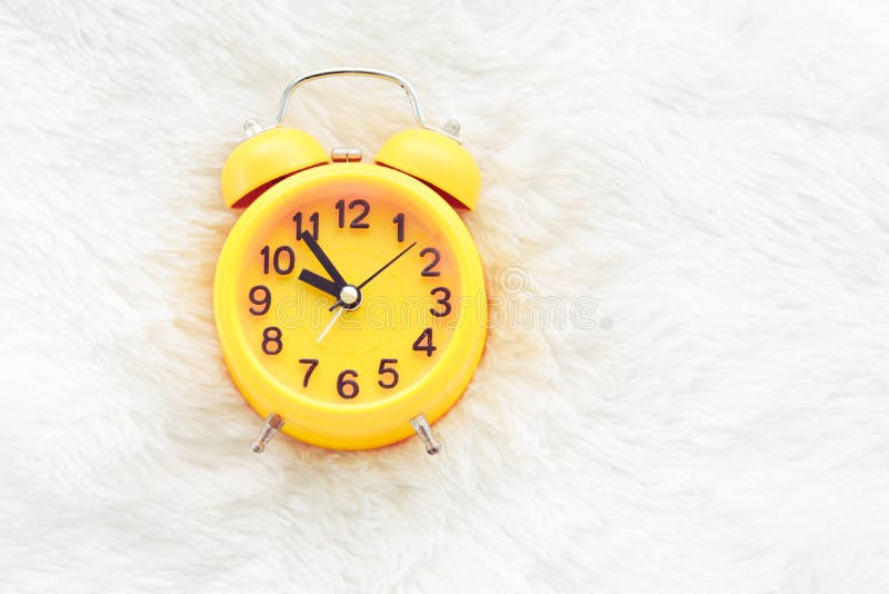 Yellow alarm clock on white wool. Late and Lazy time concept. Mo stock photography