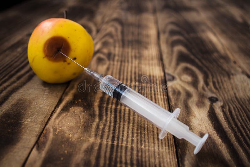 Yellow apple with rot and syringe royalty free stock photo Yellow apple with rot and syringe royalty free stock photo