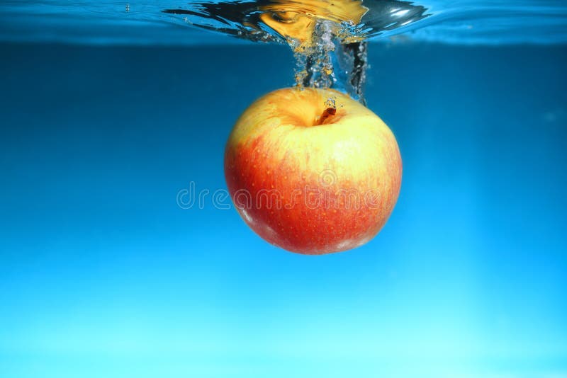 Yellow apple in the water splash over blue