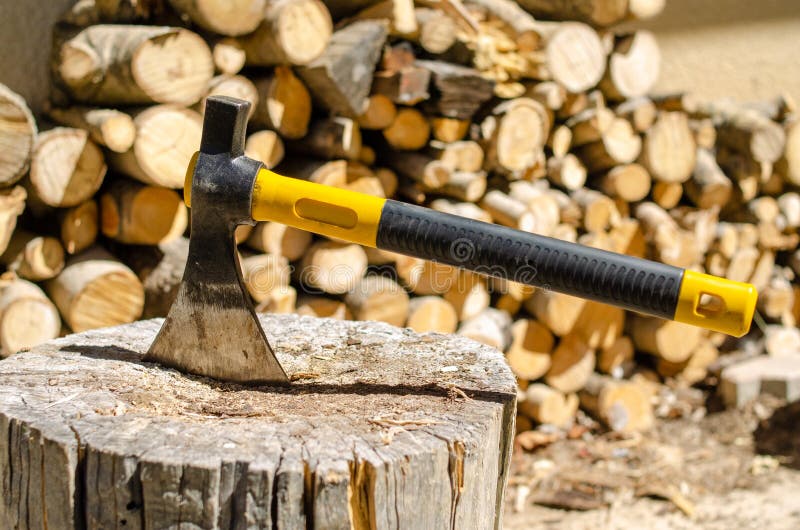 Axe with a piece of wood near a stack of logs royalty free stock photos